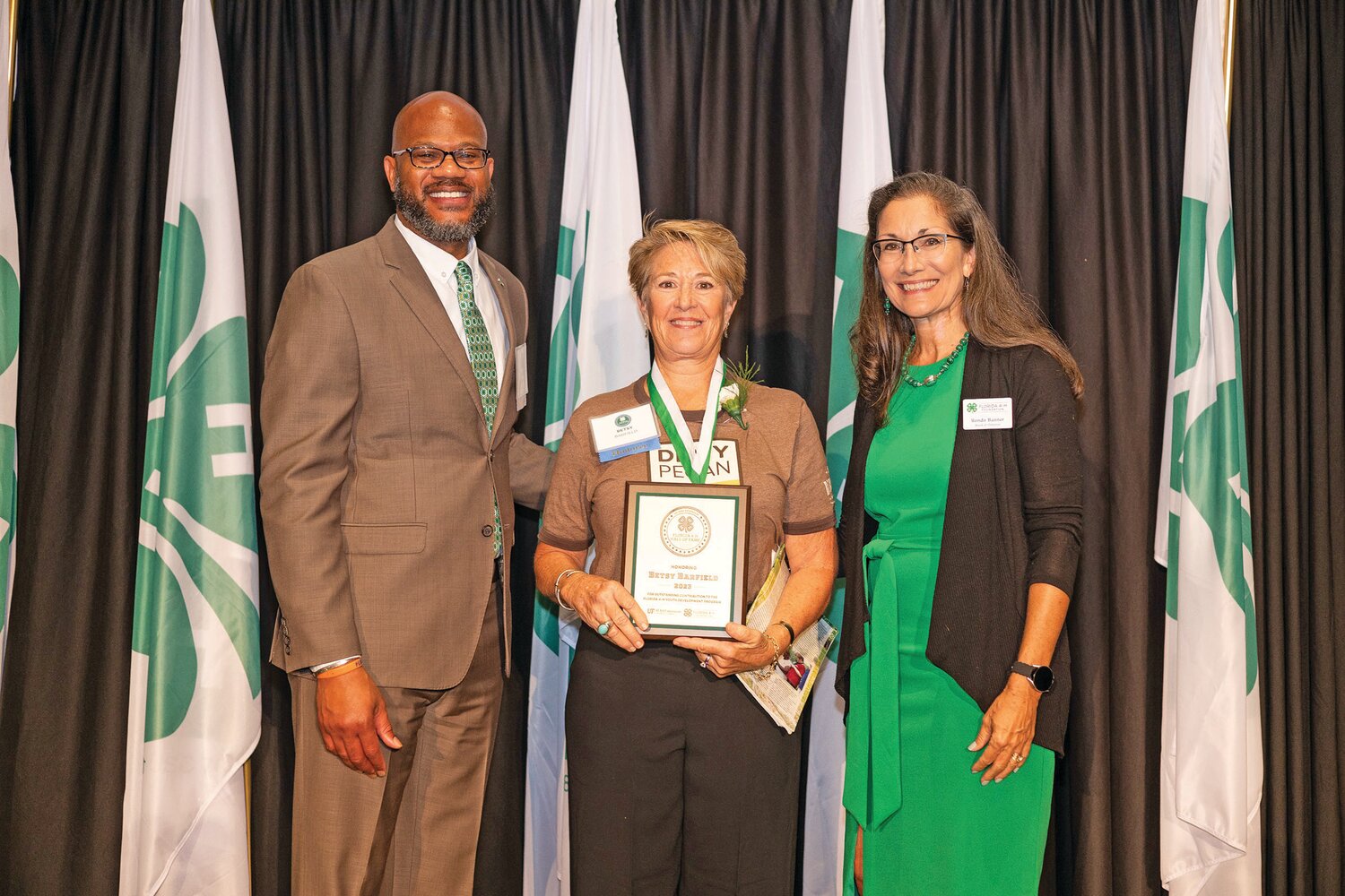 Betsy Barfield, middle, receives her induction plaque from the Florida 4-H on Aug. 3. At this ceremony, she gave a surprise donation of $10,000 to Florida 4-H to help build cabins at Camp Cherry Lake.